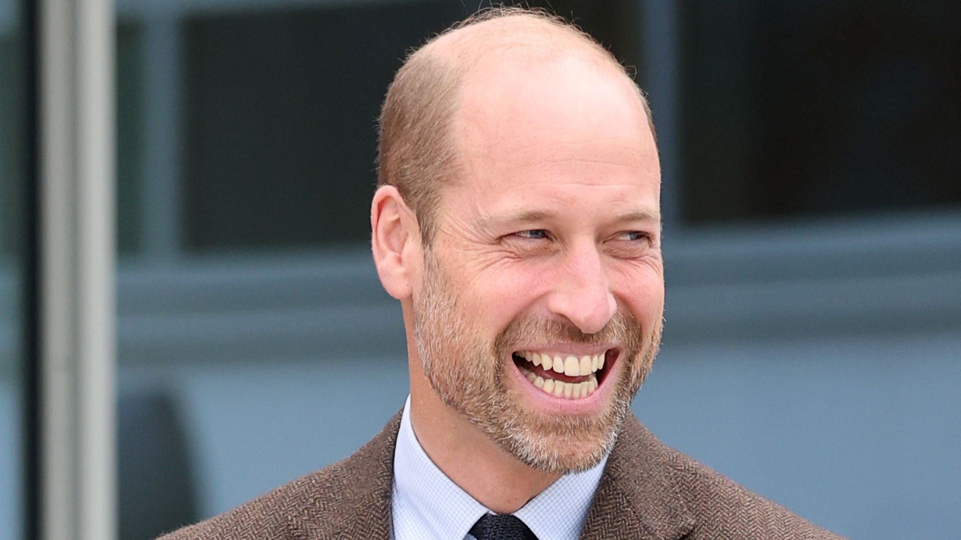Prince William smiling in brown jacket