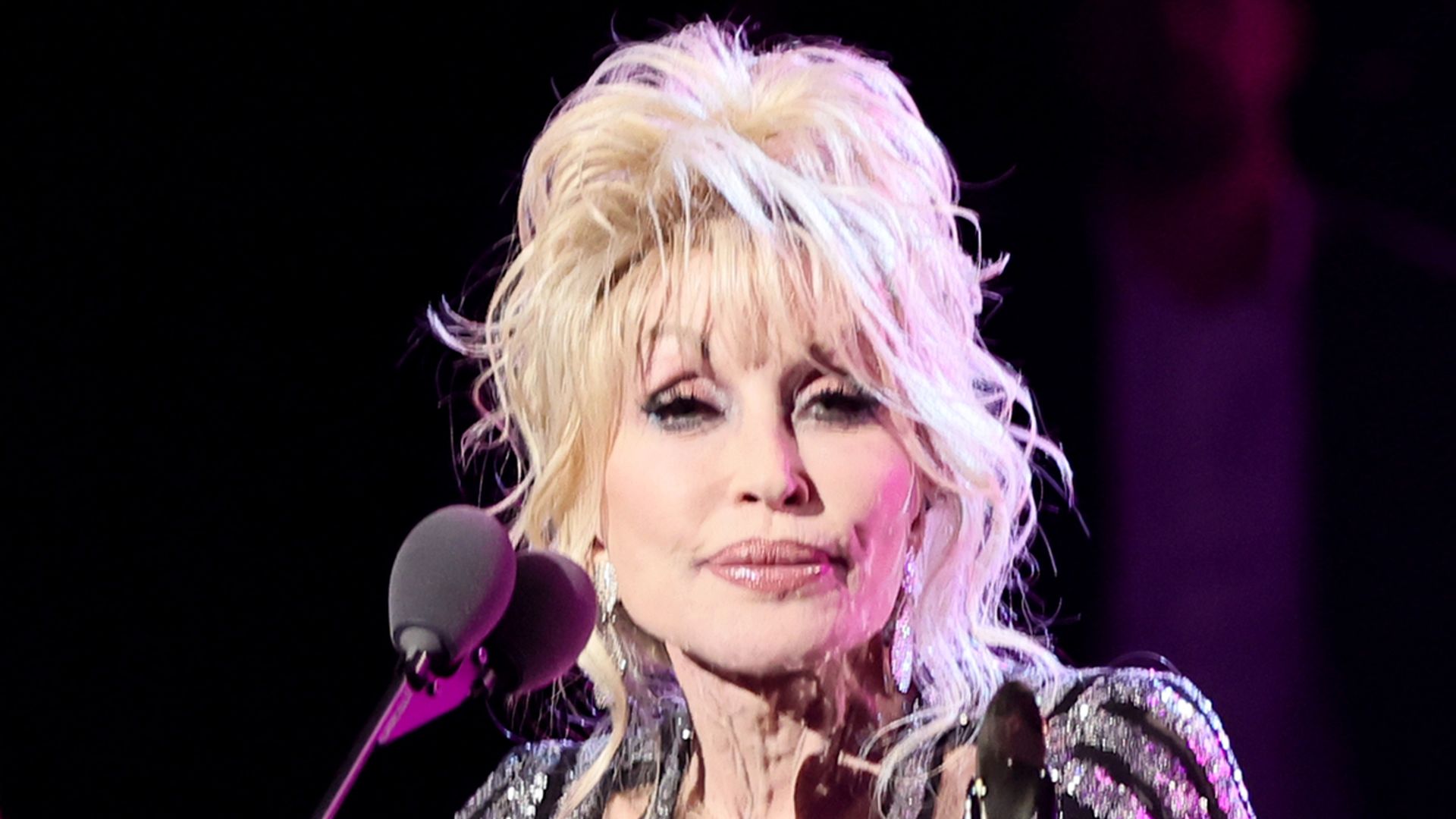 Dolly Parton performing on stage with voluminous hair and shimmering outfit
