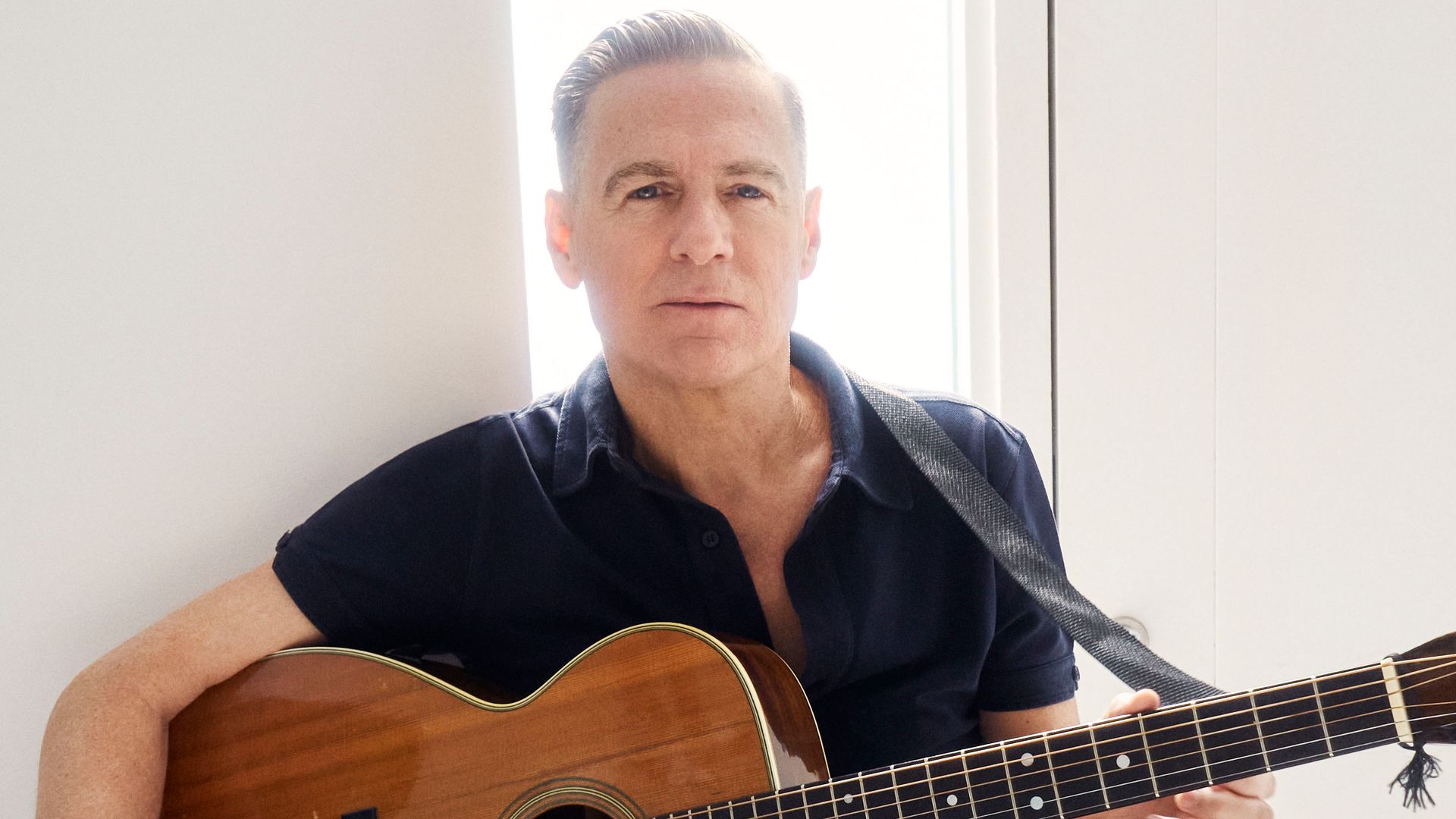          Bryan Adams  holds a guitar 