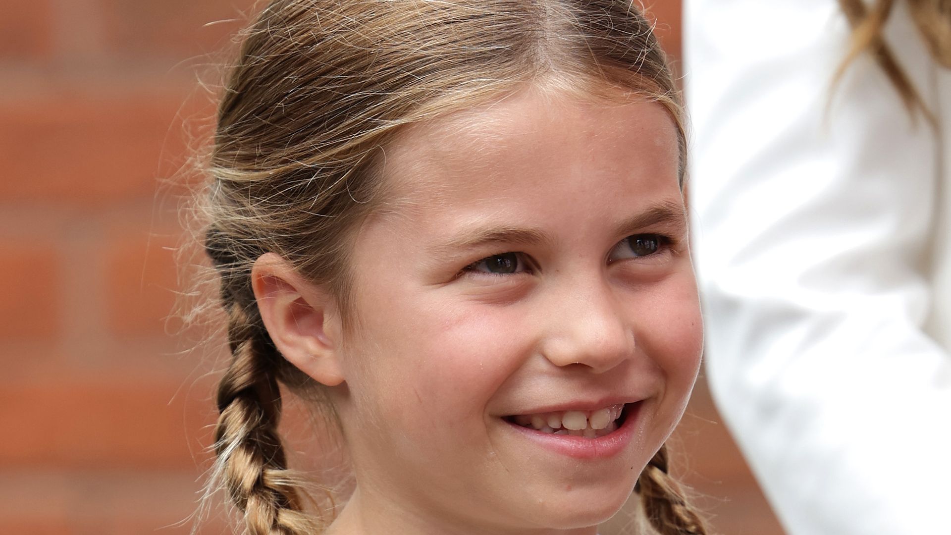Princess Charlotte looking up grinning in striped dress