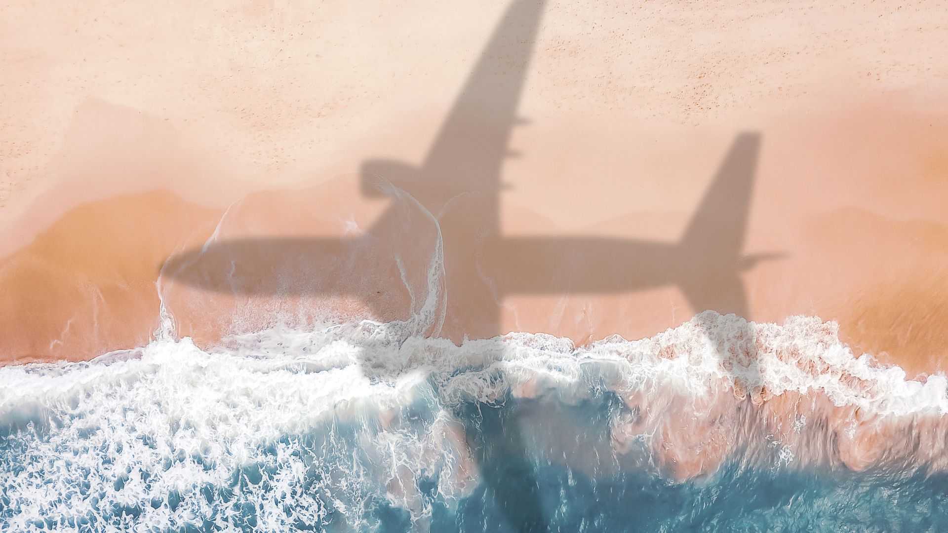 Background photo of an airplane shadow flying over a sandy beach.