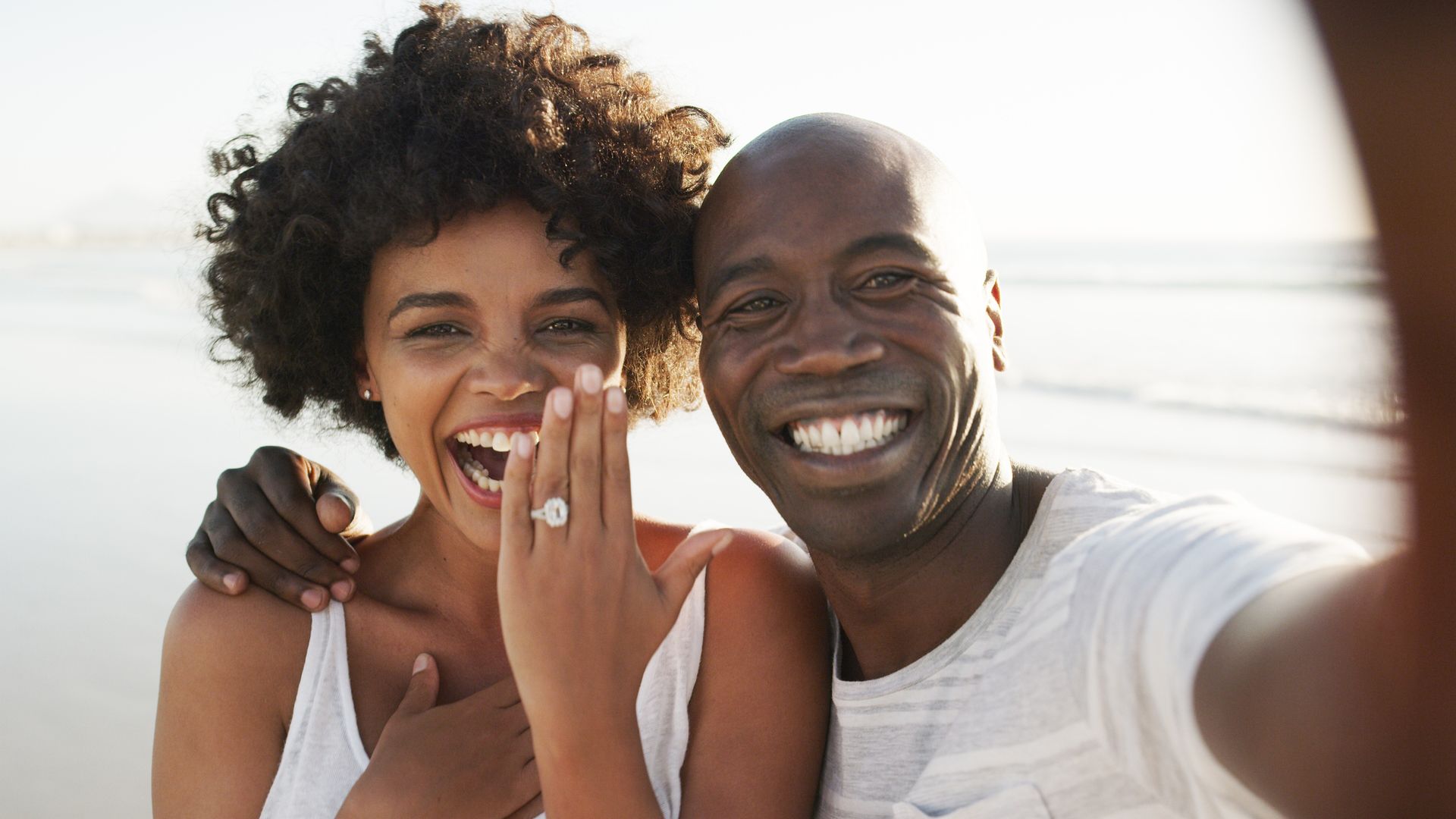 Cropped portrait of an affectionate young couple taking selfies on the beach after their engagement