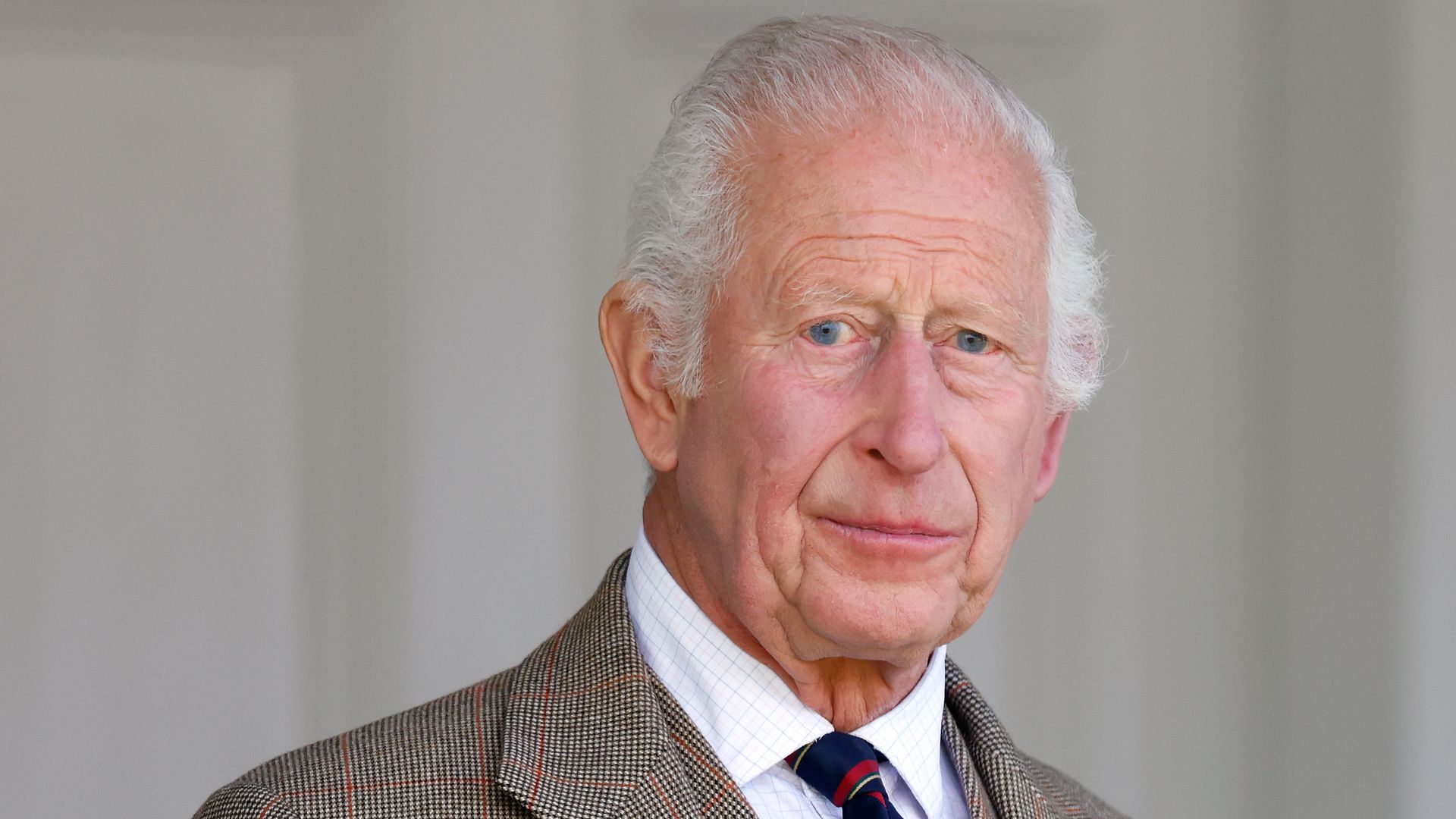 King Charles looking concerned in a tartan suit