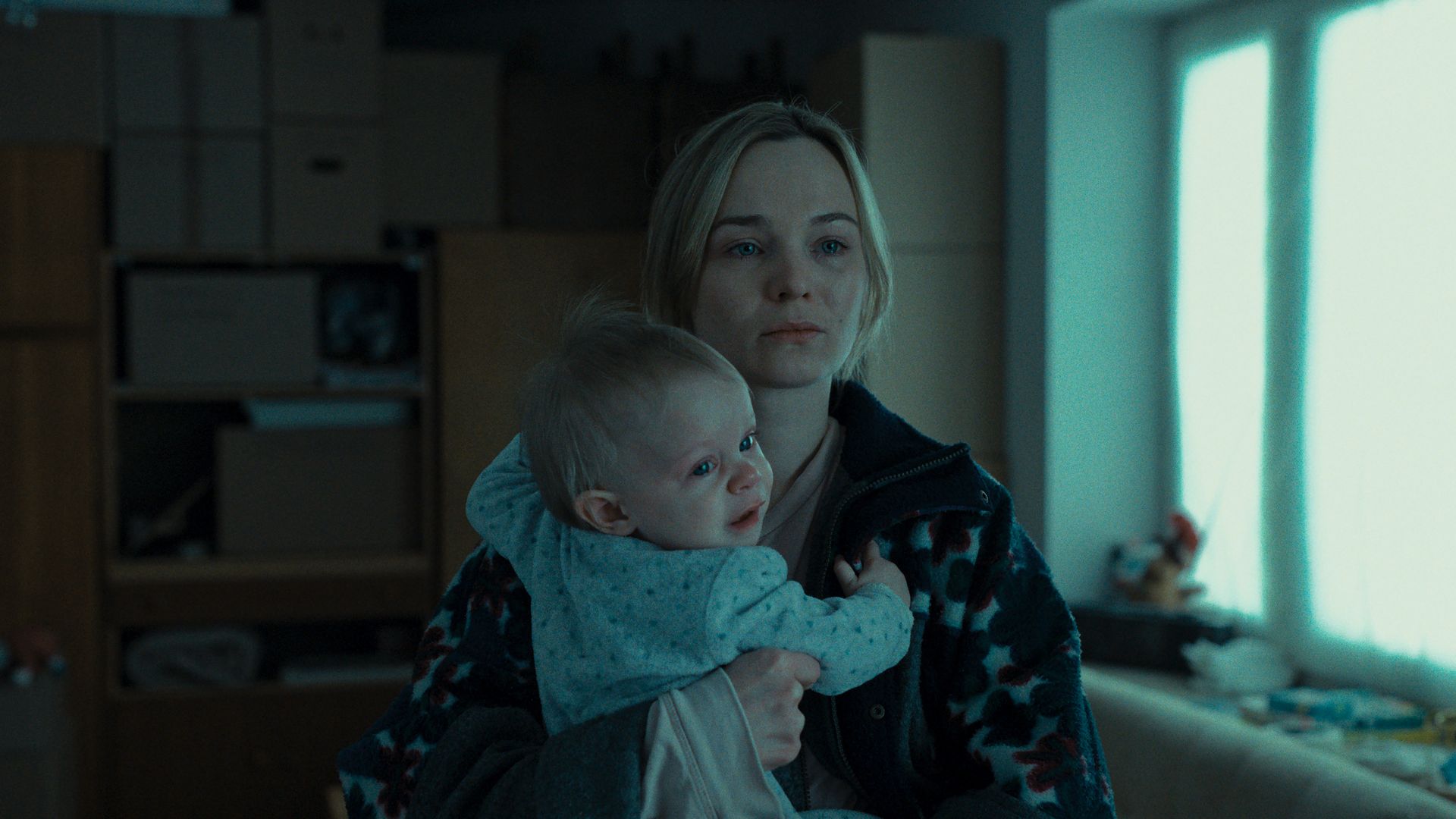 A blonde woman holding a blonde baby in Heweliusz