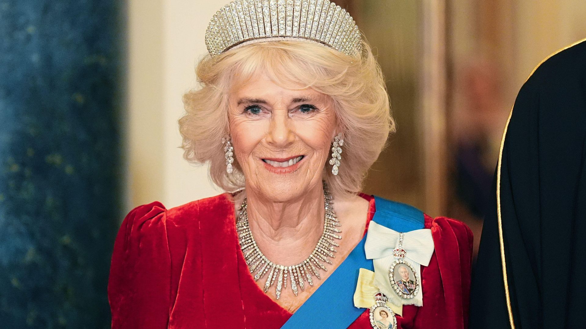 Queen Camilla wearing red dress and tiara