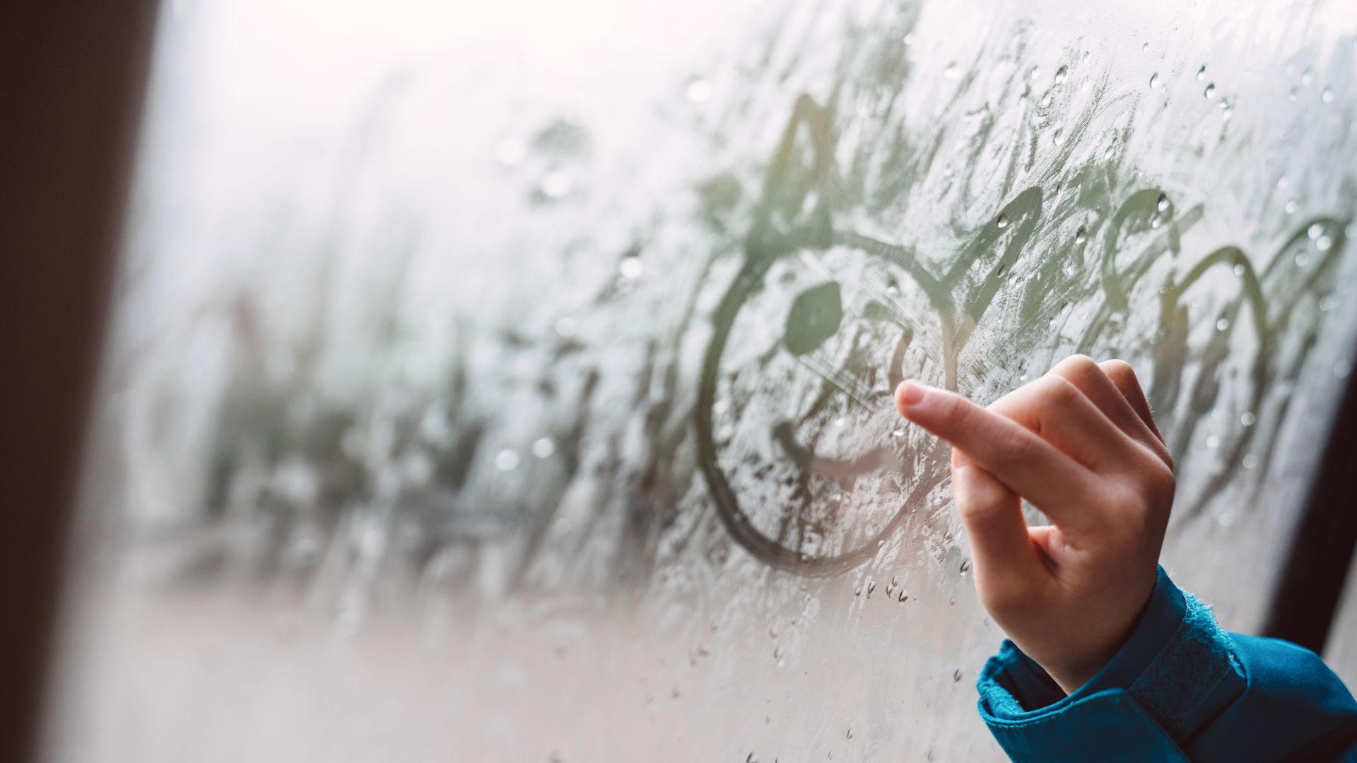 Close-up of a hand drawing on condensed car window
