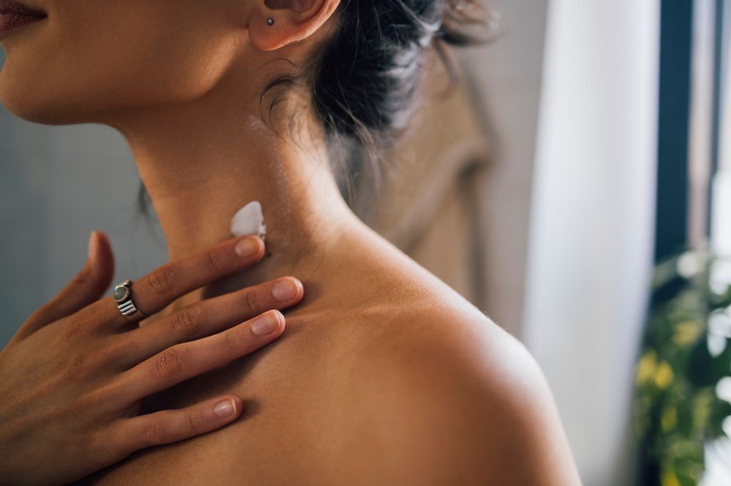 woman applying skincare on neck
