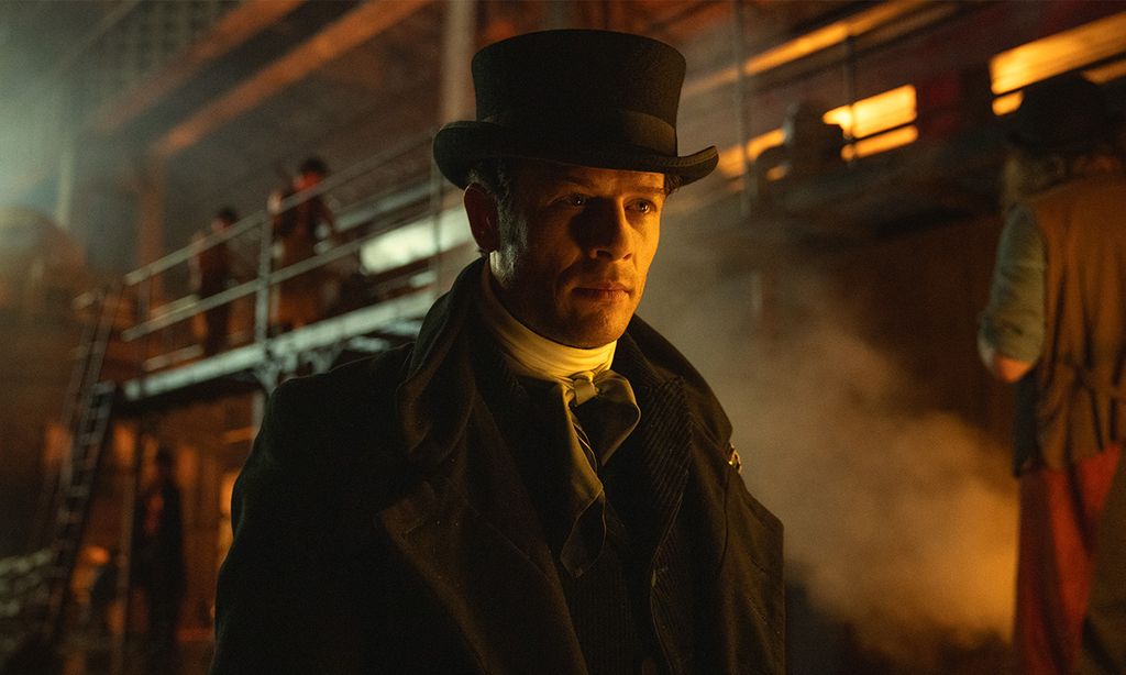 man in top hat in dimly lit factory