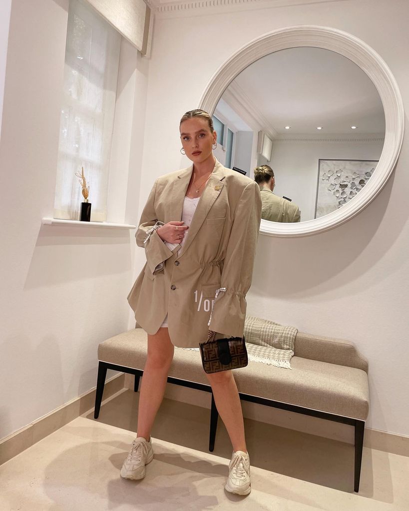 Perrie standing in front of chaise and mirror