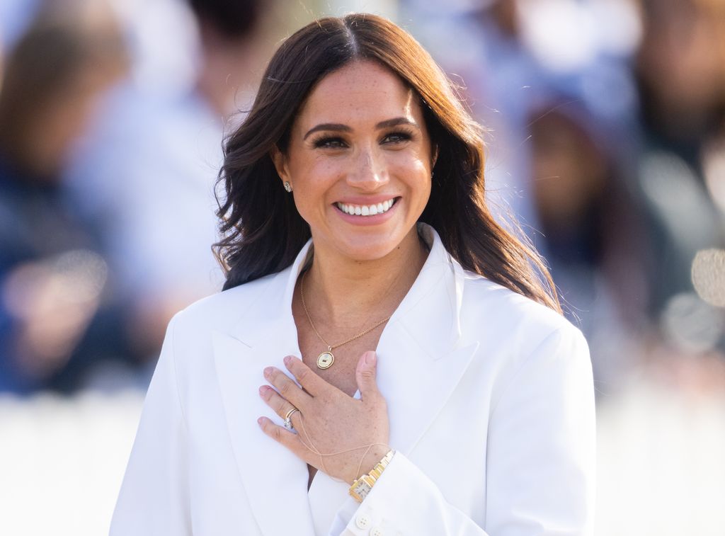Meghan Markle smiling in white suit