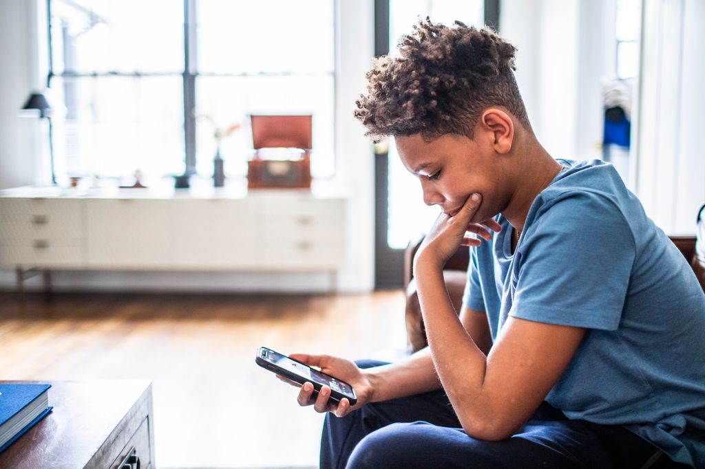 Teenage boy using smartphone in living room