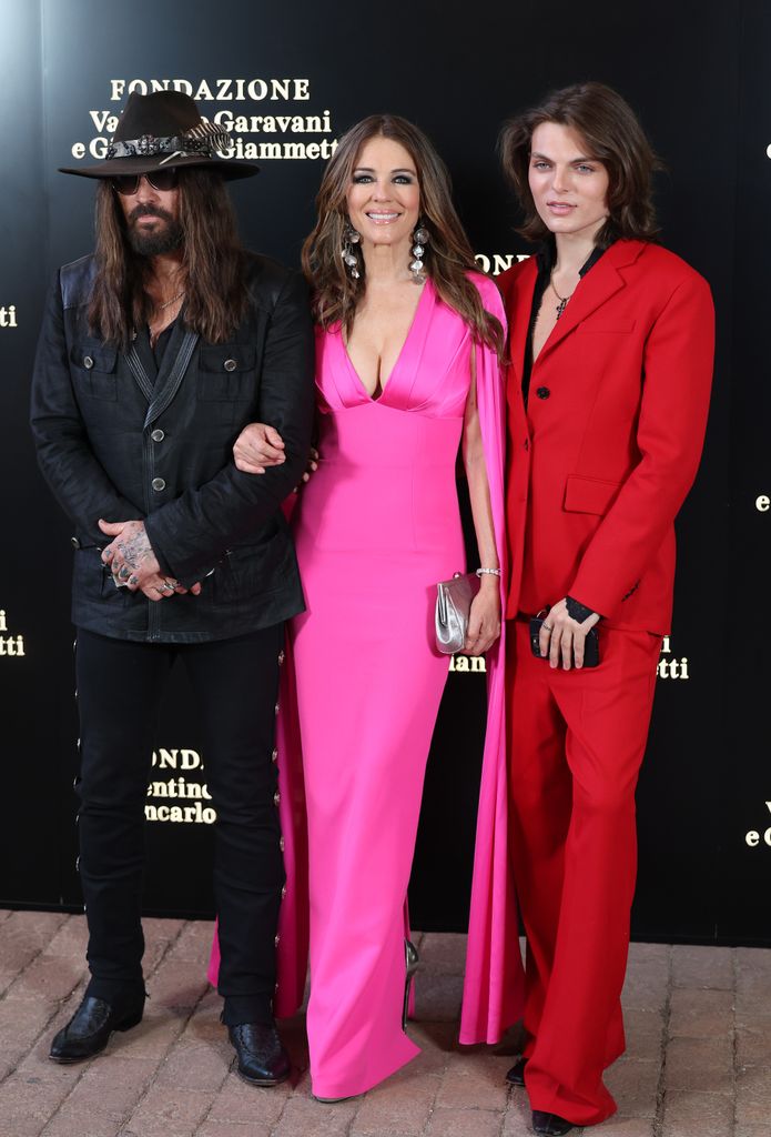Billy Ray Cyrus, Elizabeth Hurley in pink dress and Damian Hurley in red suit pose 