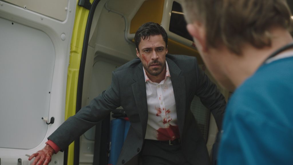 man in suit with blood on it inside ambulance