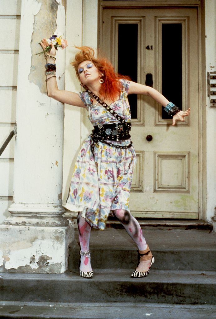 Cyndi Lauper wearing a colourful dress with layered chain belts 