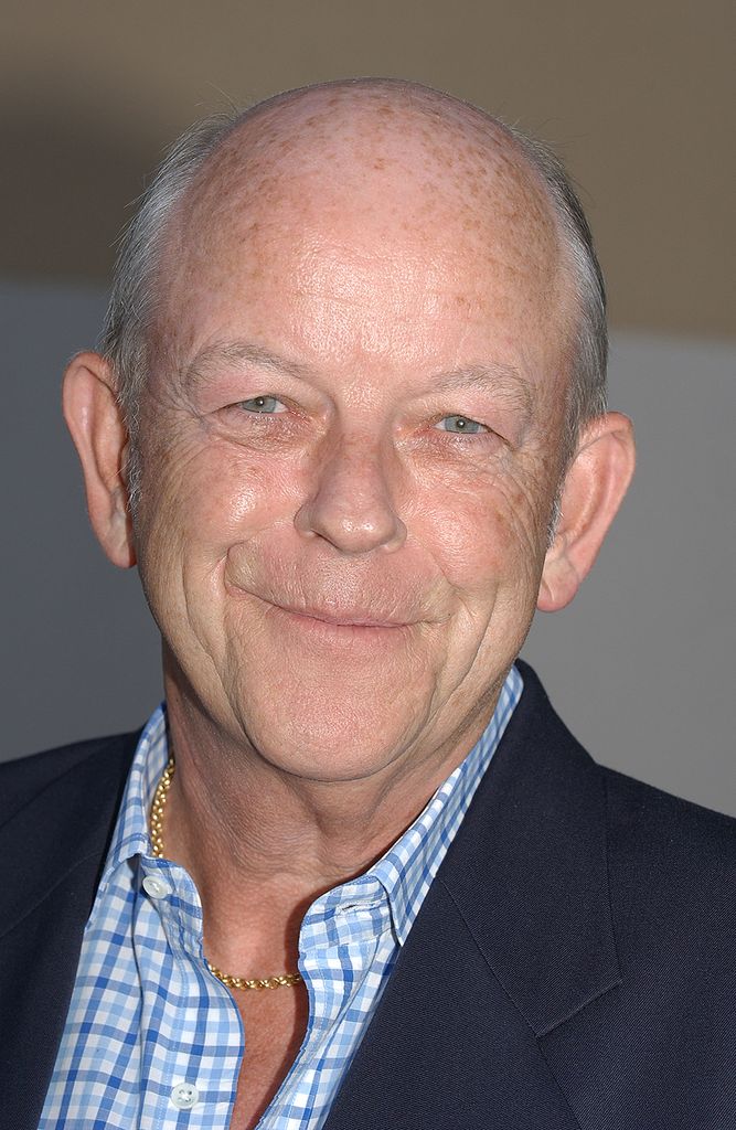 Close up of Julian Holloway wearing a navy blazer and blue checked shirt 
