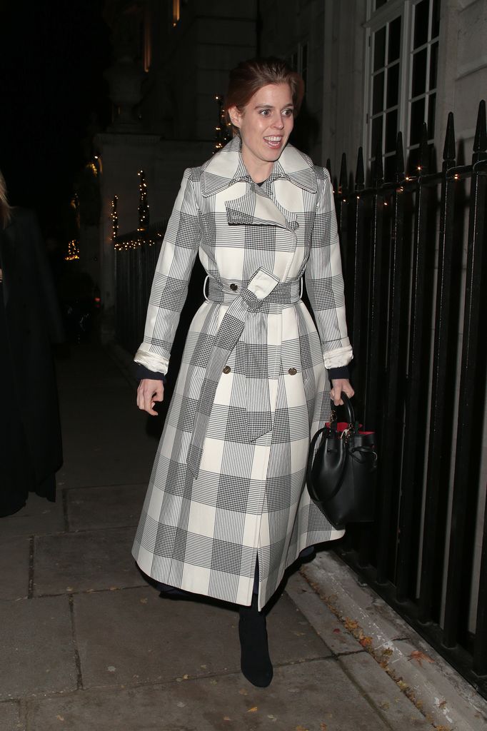 Princess Beatrice in a checked trench coat on dark street