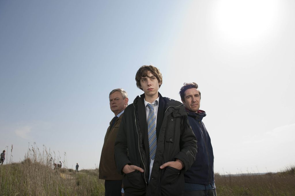 teenage boy standing in front of two men in field