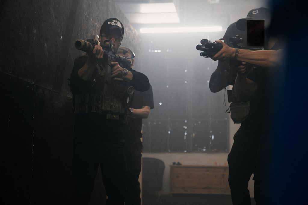 two men in dark clothing holding guns