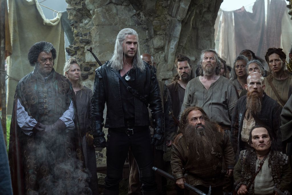 Liam Hemsworth standing with Laurence Fishburne in a scene from season four of The Witcher. 