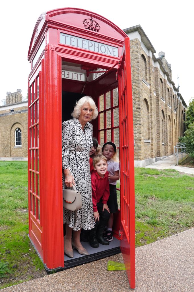 Queen Camilla and young children in a phone box