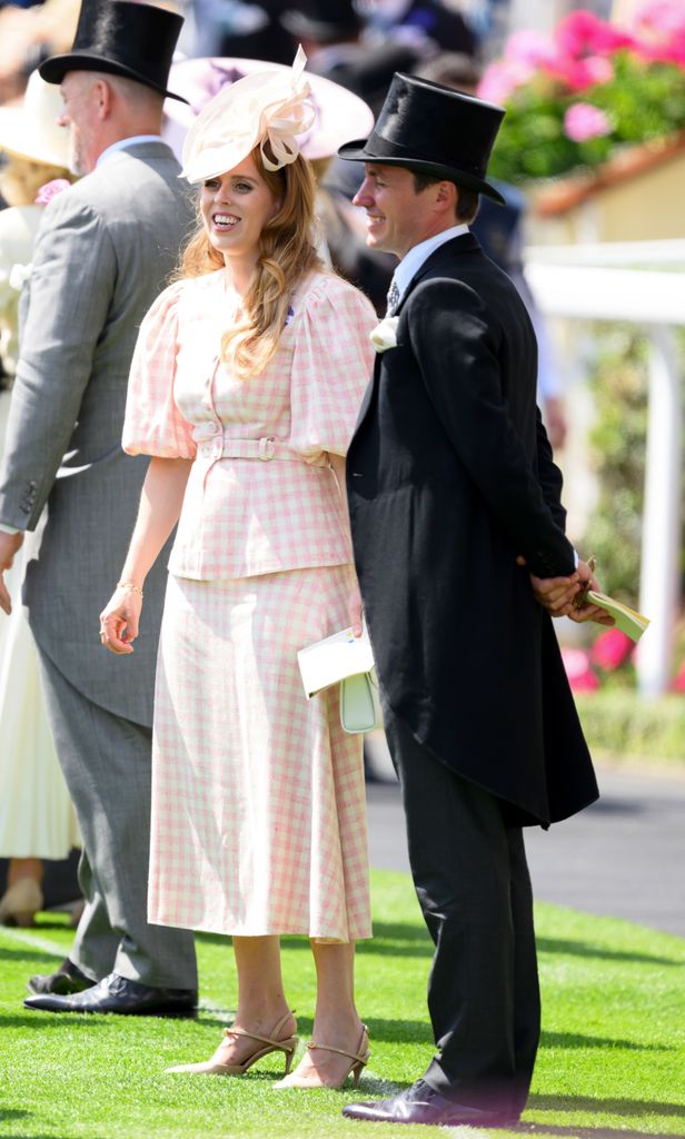 Princess Beatrice wears a blush pink gingham jacket and skirt set with a pink fascinator and white clutch at Royal Ascot standing next to Edoardo Mapelli Mozzi.