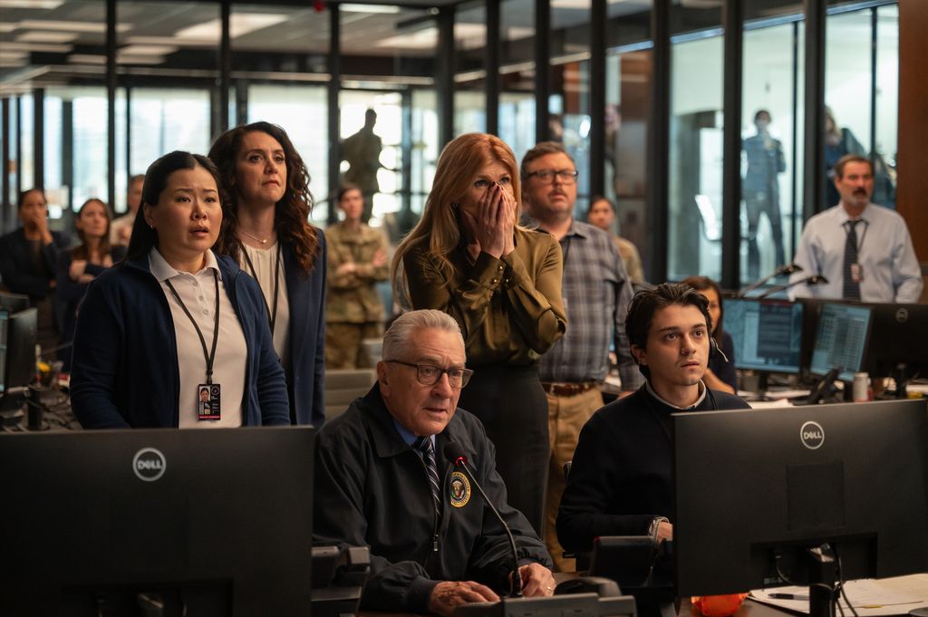 Group of people gathered around computers looking shocked