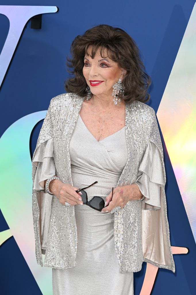 Joan Collins smiling to left in silver dress