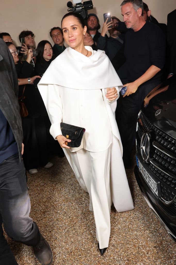 Meghan Markle in white trousers and caped top