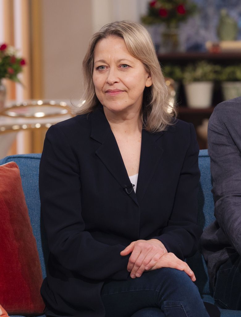 woman in black blazer sitting on sofa in tv studio