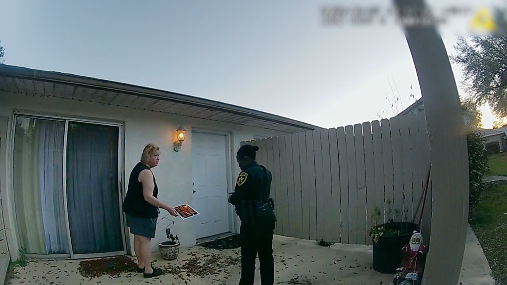 woman standing outside house next to police officer