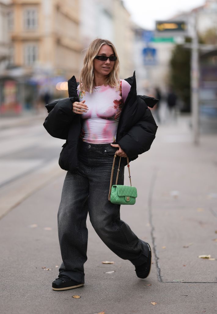 Karin Teigl seen wearing black sunglasses, KHY by Kylie Jenner black puffer / down jacket, H&M Studios grey sparkling wide leg jeans / denim pants, Jean Paul Gaultier light pink transparent body, 