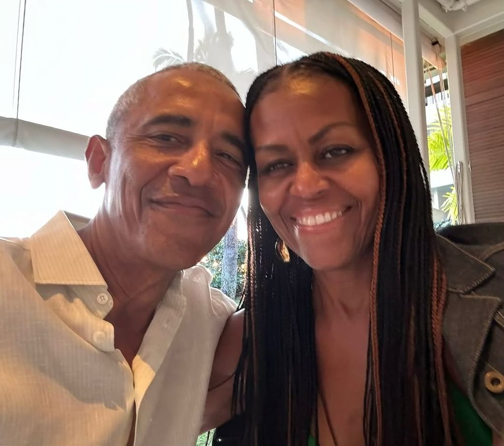 Michelle and Barack similing together with heads close