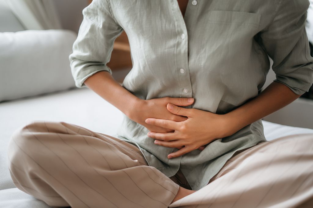 Woman in a casual shirt clutching her stomach