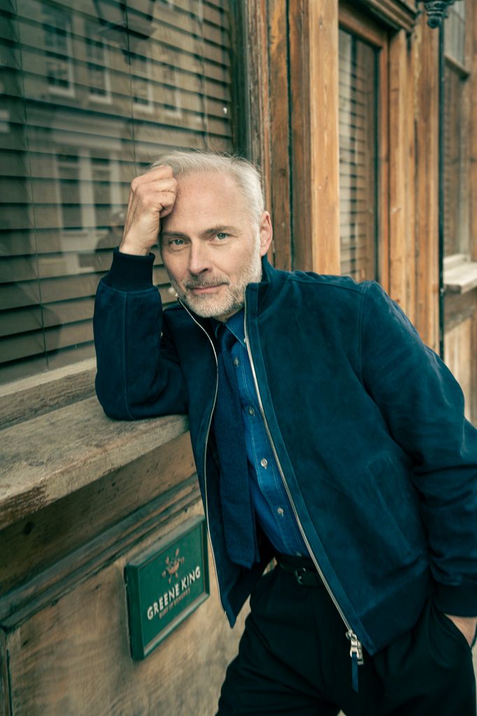 man in blue jacket leaning against window