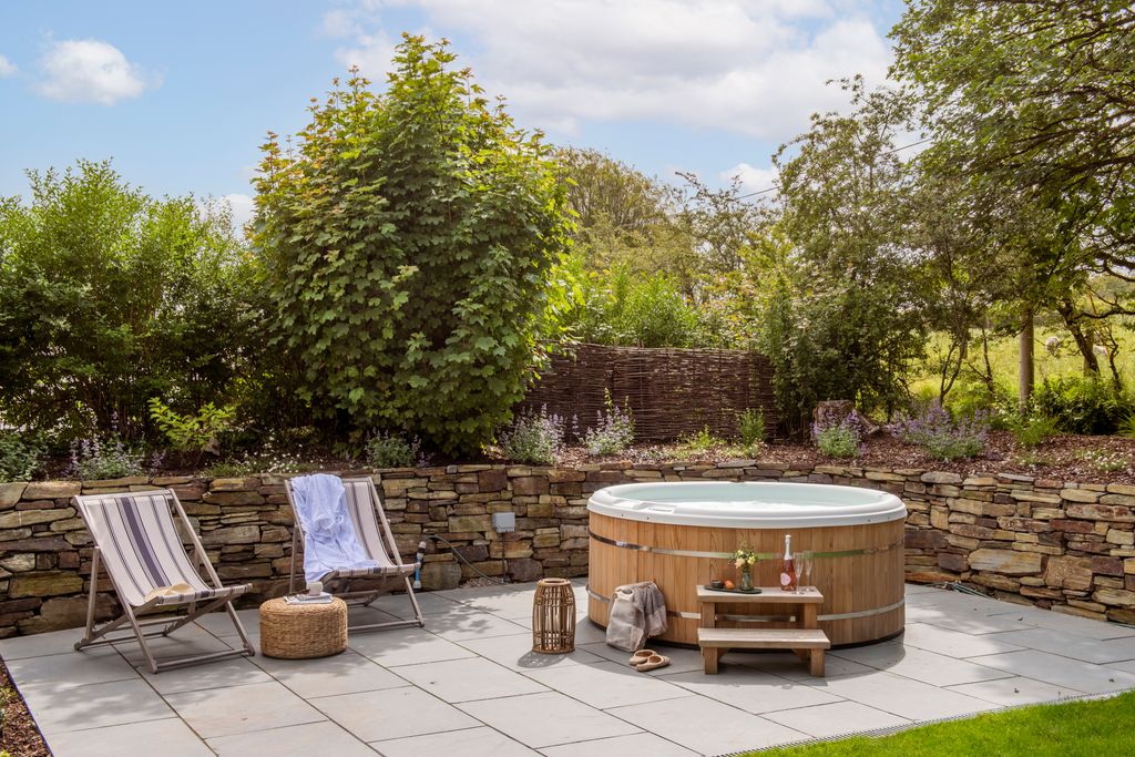 The hot tub at Moss Farmhouse is pictured  with two deckchairs