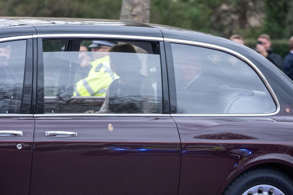 King Charles and Queen Camilla riding in the back of a car