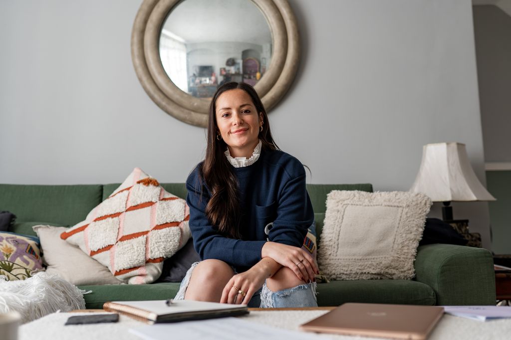Hattie MacAndrews smiling on a sofa