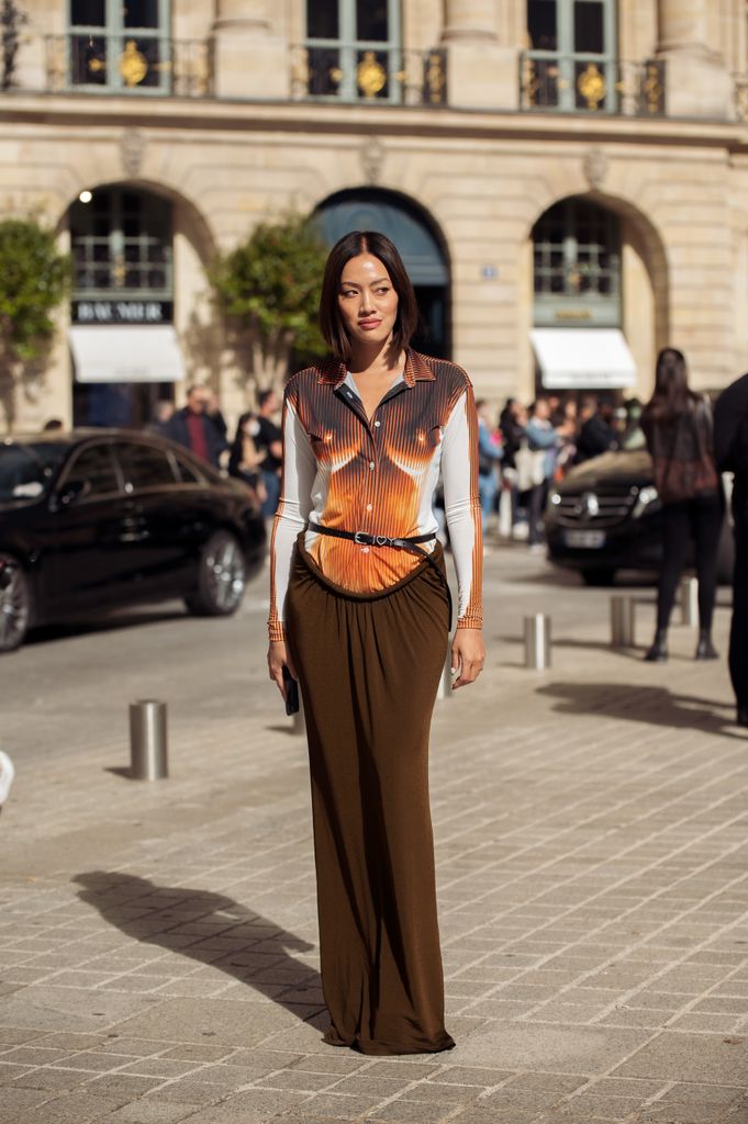 Tiffany Hsu wearing a brown, white, orange top and long brown maxi skirt outside the Chloe show during Paris Fashion Week S/S 2023 on September 29, 2022 in Paris, France.