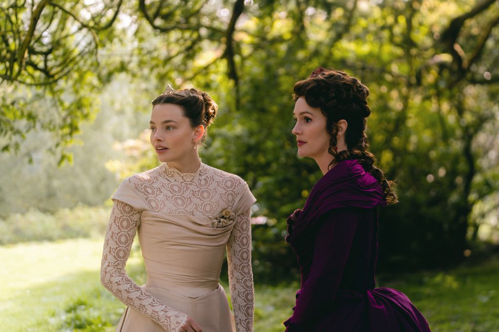 two women in period dresses standing in field