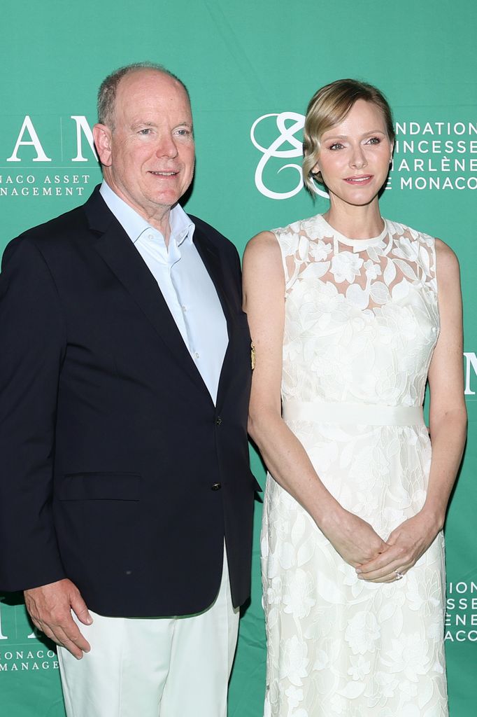 Prince Albert II of Monaco in blazer beside Princess Charlene of Monaco in white lace dress