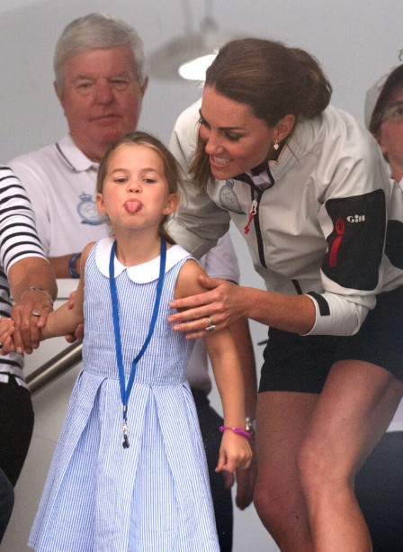 Princess Charlotte sticking her tongue out and Princess Kate holding her back