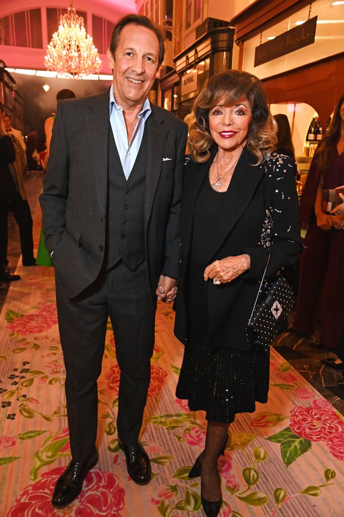 Percy Gibson dan Dame Joan Collins berpose di butik dengan pakaian hitam