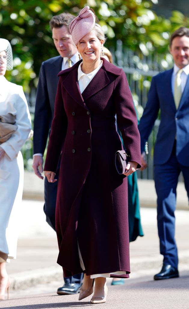 Sophie in burgundy coat and pale pink fascinator