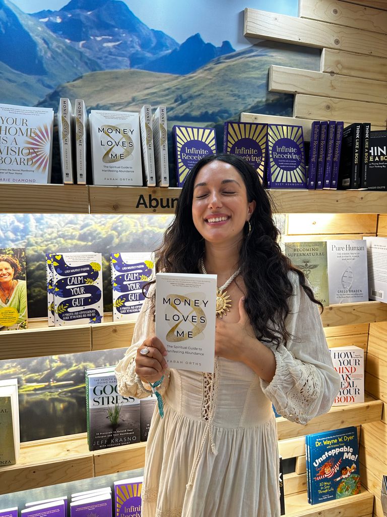 Farah in a book shop, holding her book 