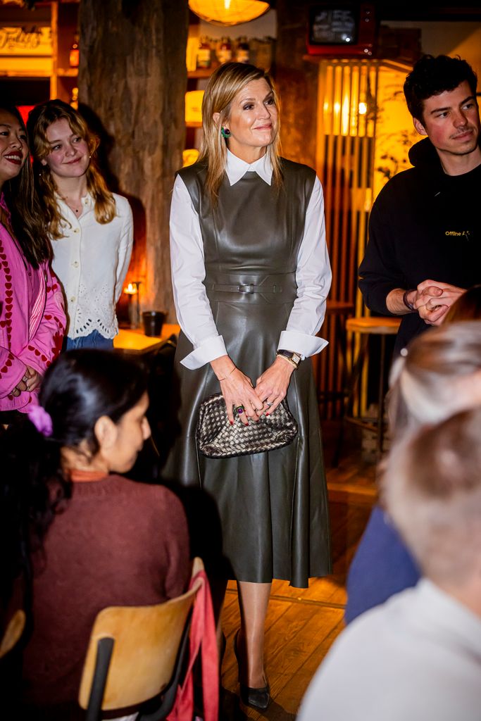 Queen Maxima in room of people in khaki leather dress