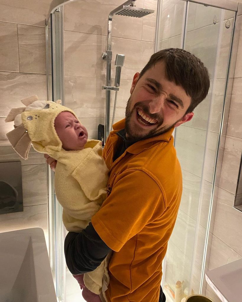 Pete Sandiford laughing as he cuddles his crying son Jimmy