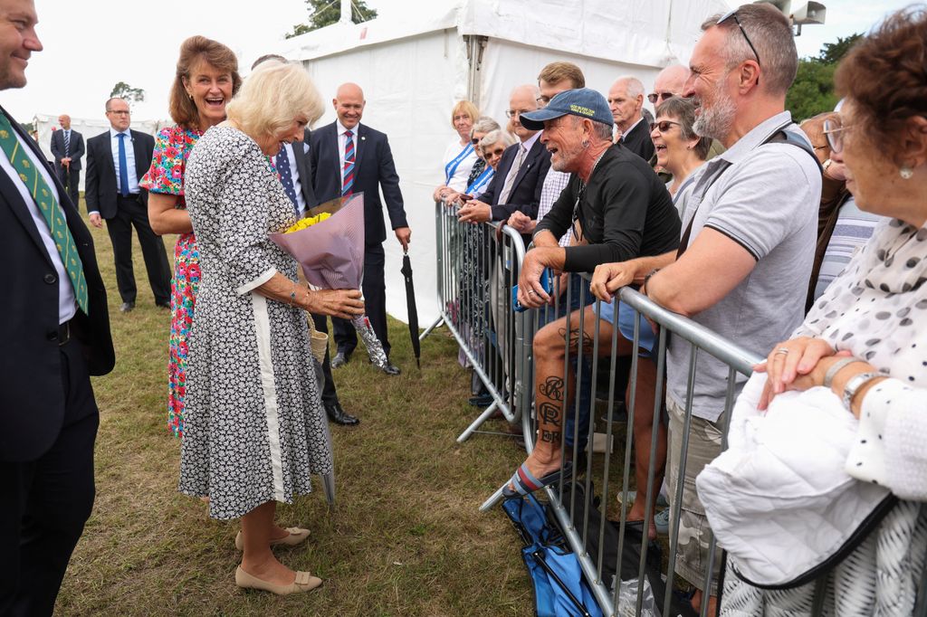 Queen Camilla reacts as she receives flowers from Phil Smith, a royal super-fan,