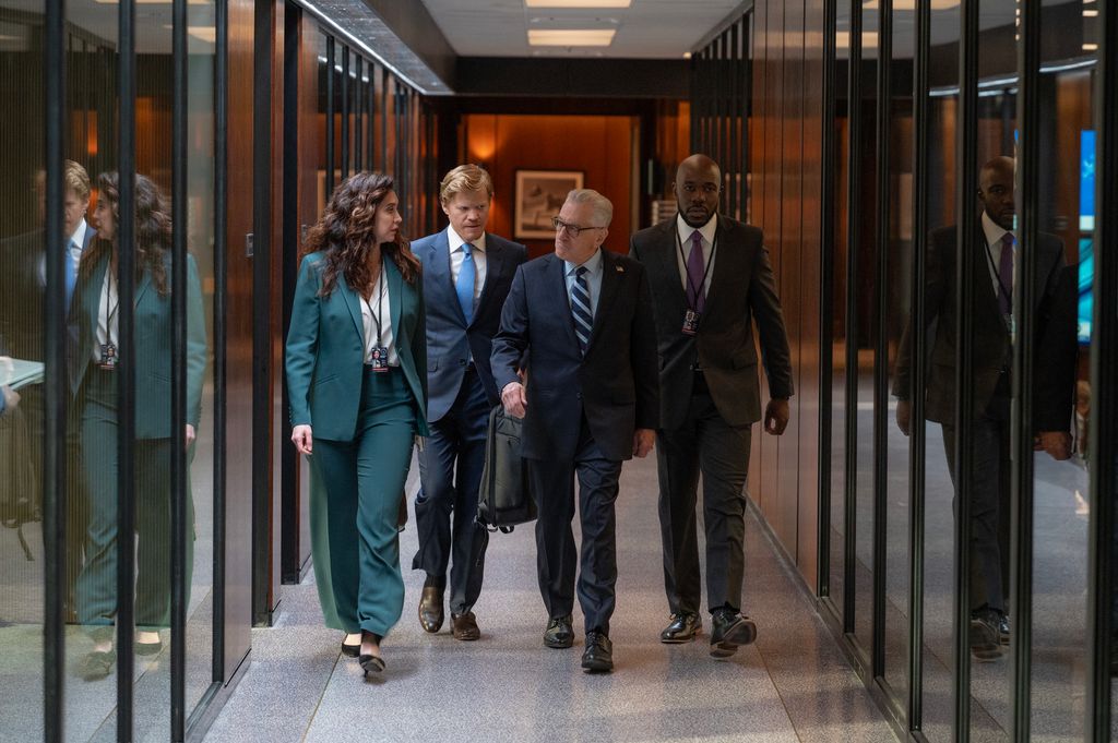 Four people in suits walking down hallway