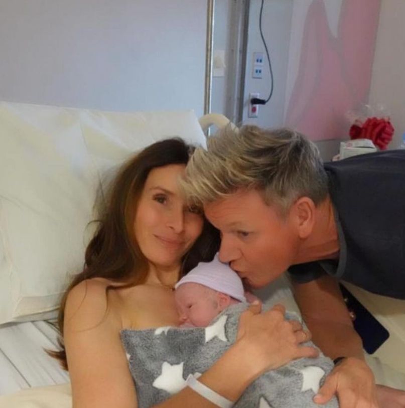 Tana Ramsay holding a newborn baby close to her chest as Gordon Ramsay kisses the baby's head