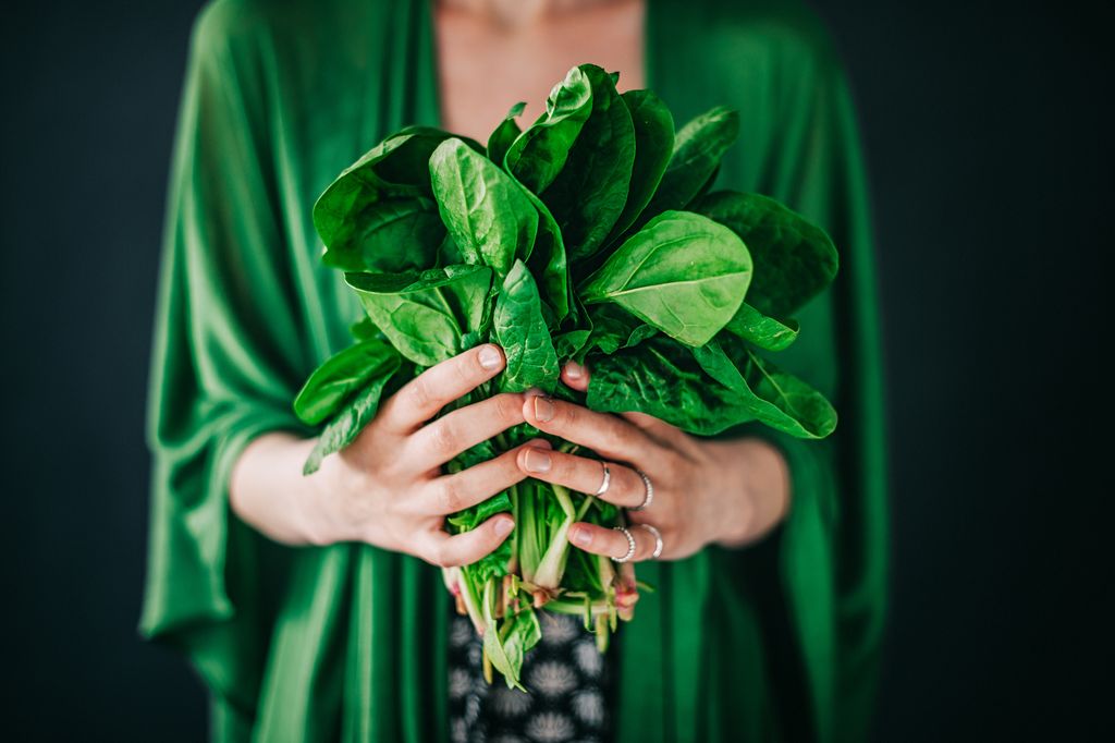 Young woman holding spinach leaf salad